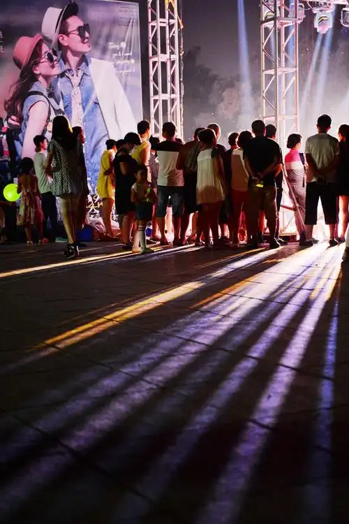 夏夜晚会,观众在看节目,舞台的灯光从人群中透出.