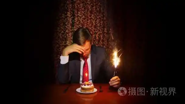 一个孤独的人庆祝的节日,他独自坐在一张桌子一个蛋糕和一支蜡烛.