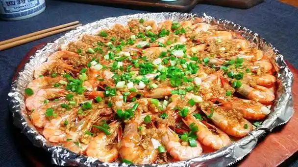 铁板蒜蓉基围虾撒上小米椒圈和葱末,浇一层热油.蒜蓉粉丝蒸虾完成!