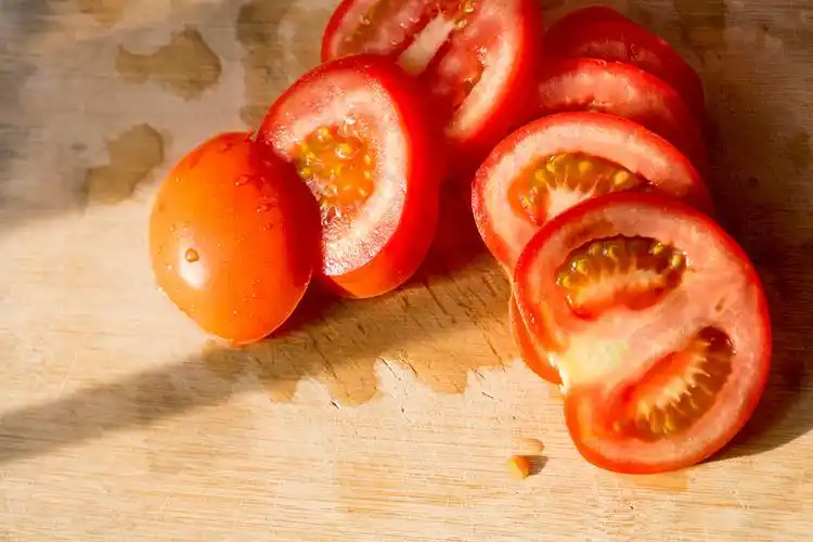 阳光下放在砧板上切开的西红柿静物特写