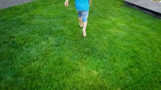 光着脚的小男孩在公园里的新鲜草地上奔跑的照片照片