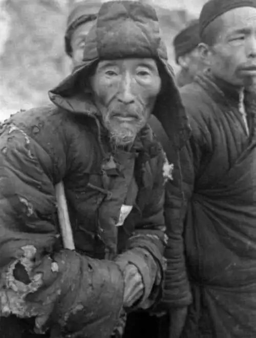 图中大爷身穿破烂衣服,双目中闪烁着恳求活命的希望.