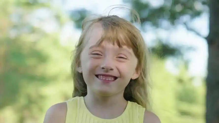 小快乐女孩看着镜头笑.一个有趣的小孩的户外肖像.视频