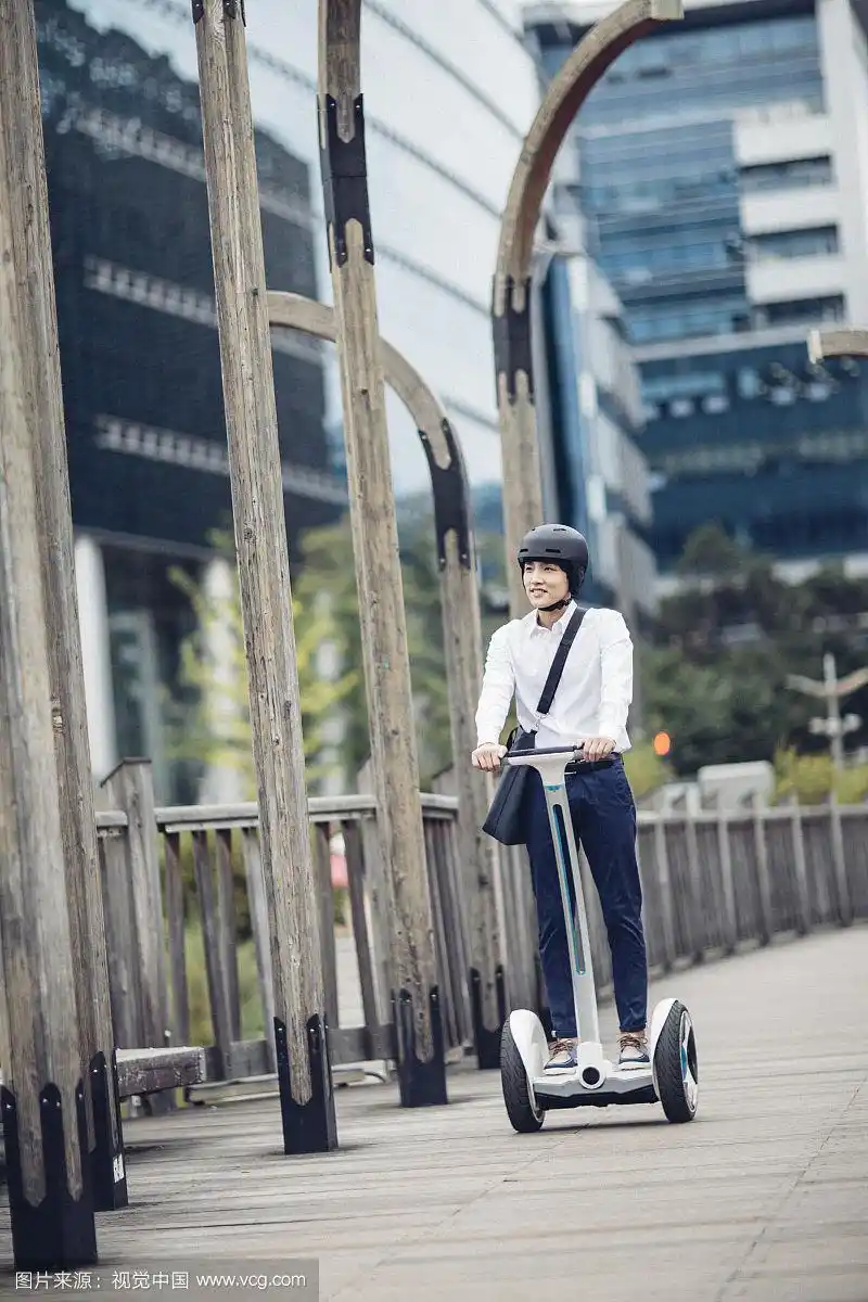 男人戴着头盔在街上骑电动车的照片