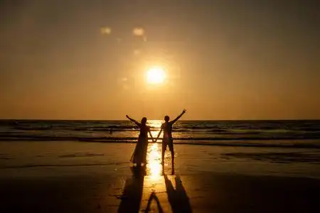 一对度假情侣在夕阳下漫步在海滩上相爱照片