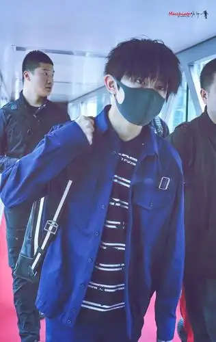 千玺头发微微烫了小卷发,背着双肩包,戴着无线耳机