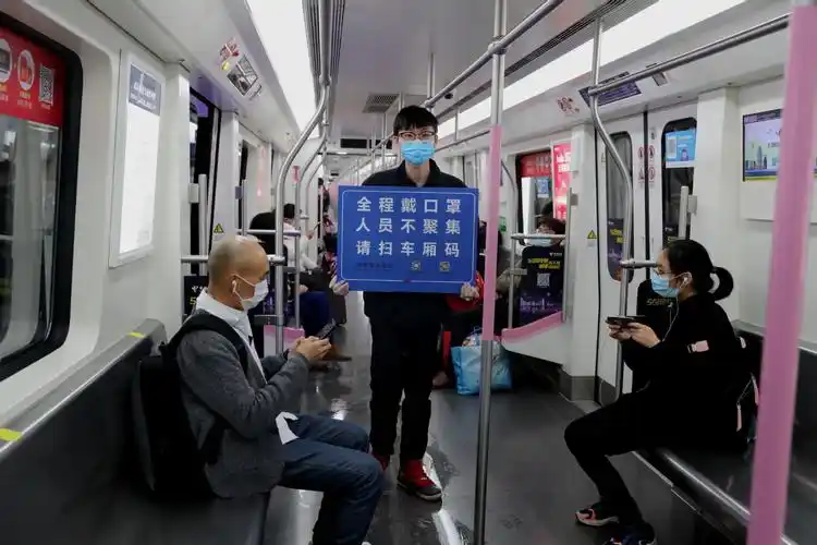 3月29日,武汉地铁2号线上,工作人员提示乘客"戴口罩 不聚集".