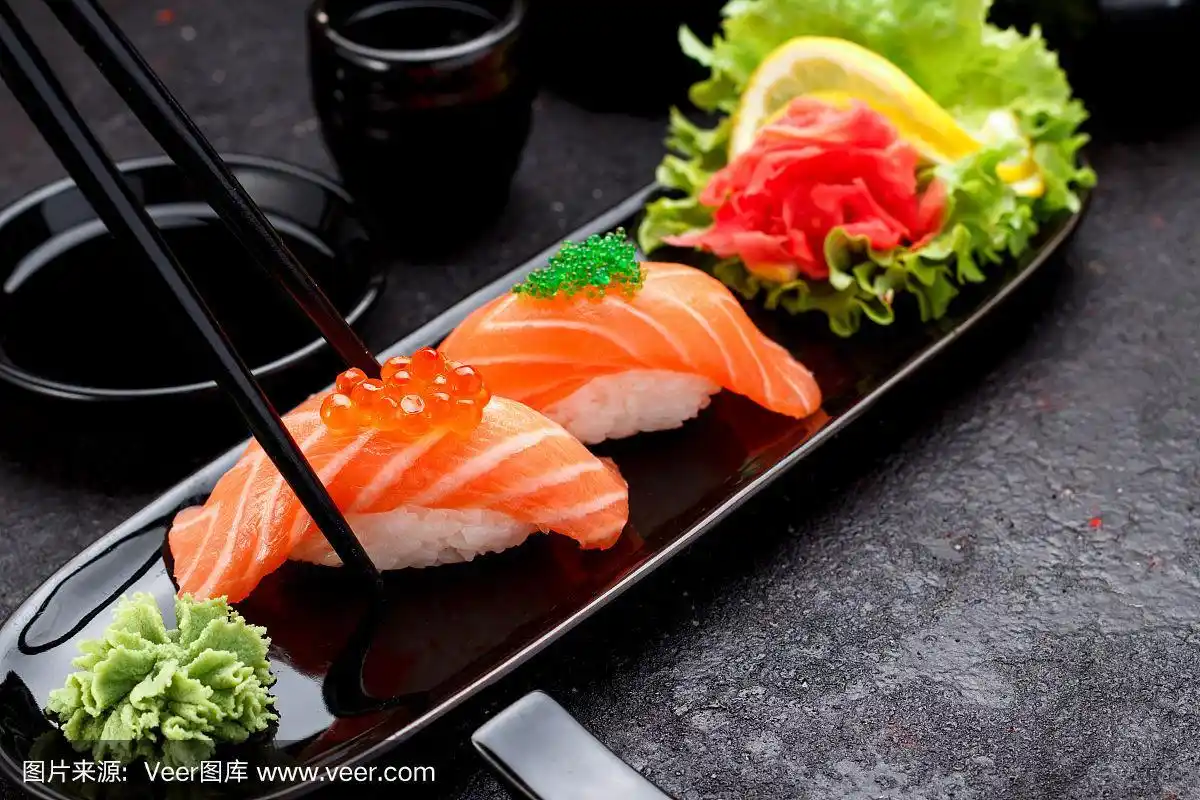 用筷子夹在黑色盘子里的三文鱼寿司手握寿司.