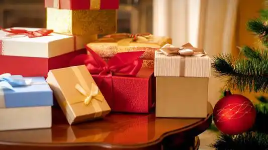 在客厅靠着圣诞树和壁炉的木桌上放着一大堆圣诞礼物和礼物的特写照片