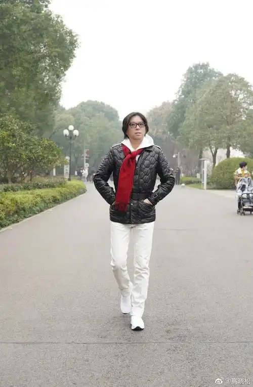 照片中,高晓松系着红色围巾,上身穿着黑色外套,下身穿着白色长裤,配一