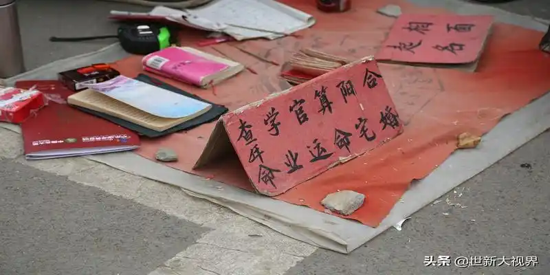 这位帮人看相的老人摊前摆放算命起名字样的红牌子还有卦书和竹签世新