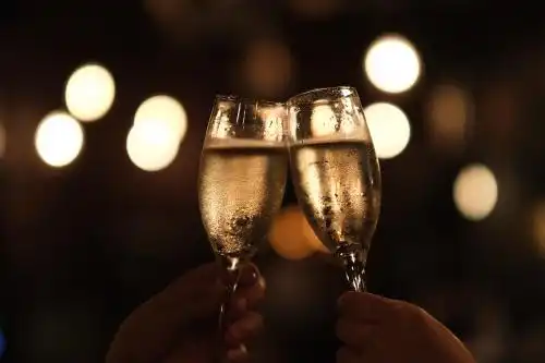 夜晚的光斑前两只手举着酒杯干杯庆祝