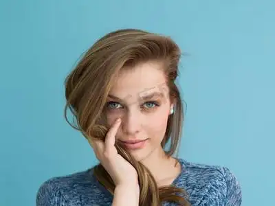 一位美丽积极的年轻女子的肖像,她在蓝色背景中玩着她柔滑的长发