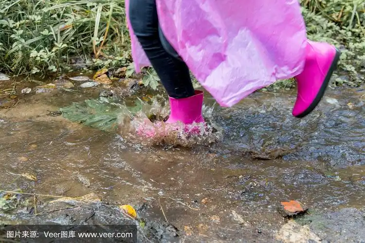 穿着胶靴和雨衣的女人在雨中行走