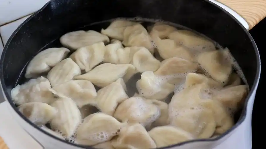 锅里水烧开后,下入饺子煮熟.