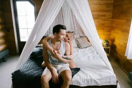 漂亮的女人和迷人的男人穿着家居服,坐在床上拥抱.照片