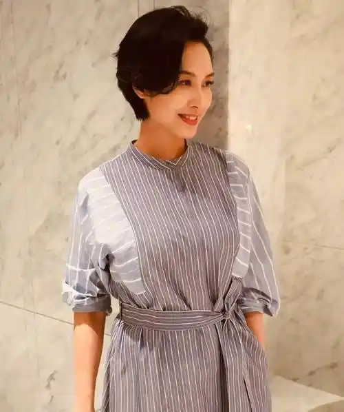 照片中的朱茵身穿灰蓝色格纹拼接衬衣裙,腰带虚虚打个结,勾勒出美好