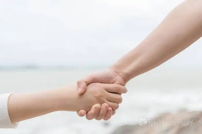 男女手牵在一起, 在模糊的海和天空背景为爱和情人节和友谊日概念照片