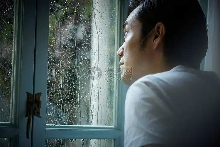下雨天看向窗外的男性