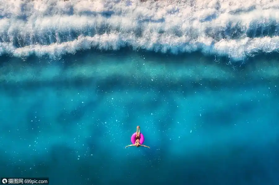 鸟瞰轻女子游泳粉红色的游泳环透明的绿松石海,土耳其奥卢德尼斯夏天