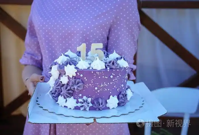 年轻漂亮的女孩穿着紫色的裙子手里拿着一个15号的生日蛋糕蛋糕上装饰
