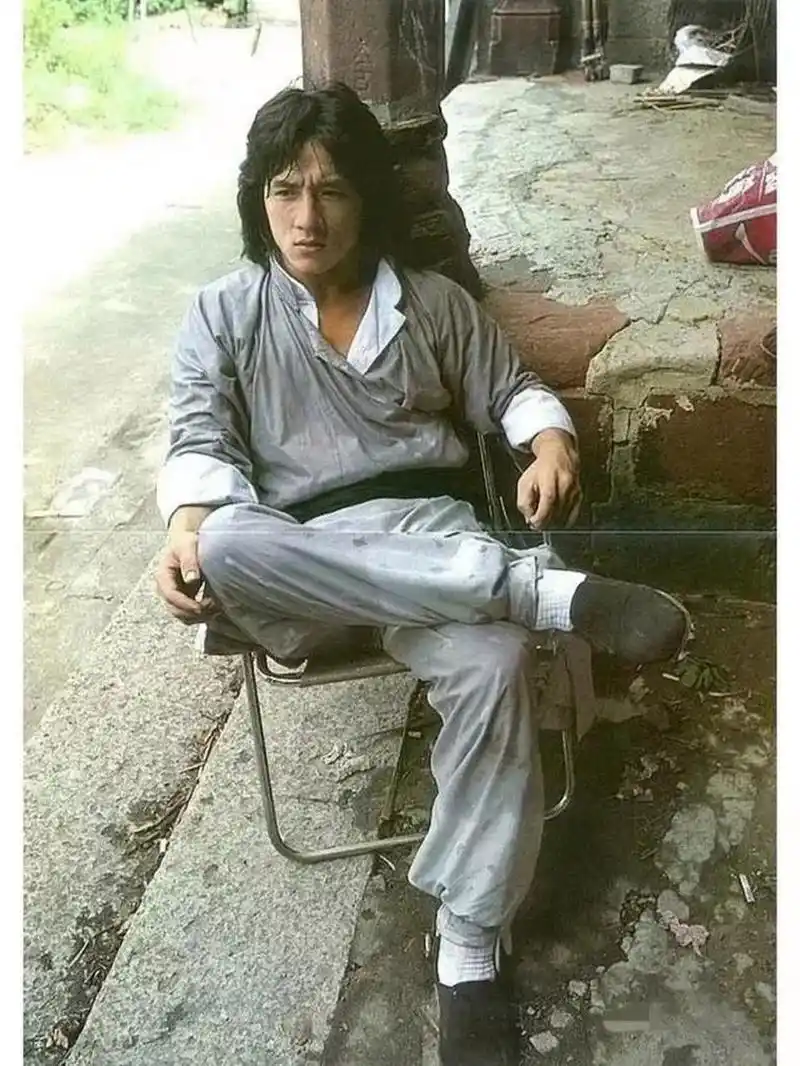 1980年,有一张年轻的成龙坐在椅子上休息的照片,展现了他年轻帅气的一