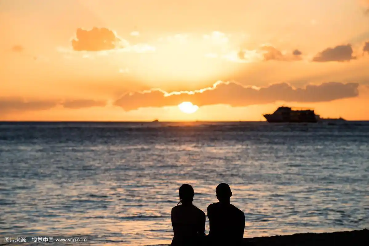 一对情侣坐在沙滩欣赏落日