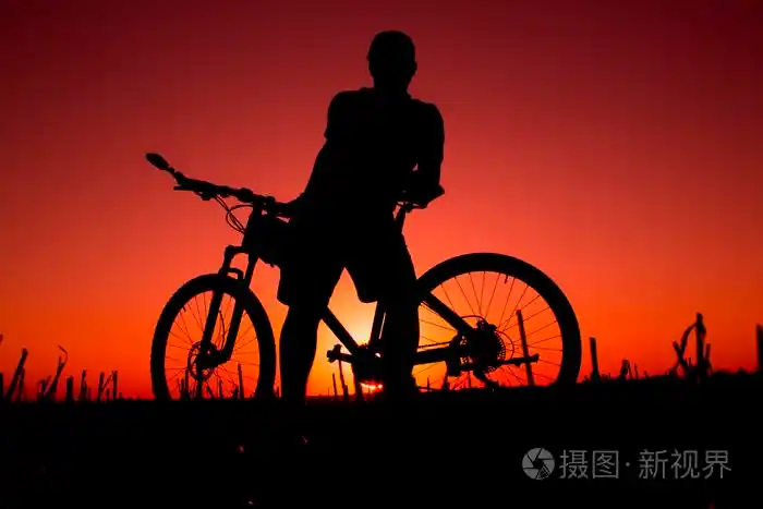 日落和剪影背光骑自行车的人