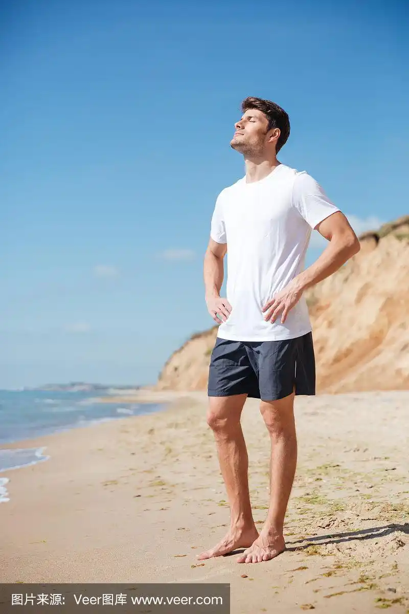放松的男人赤脚站在沙滩上