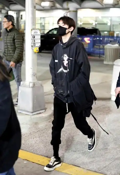 只见照片中易烊千玺戴着口罩,身穿黑色外套黑长裤黑鞋子内搭粉色内衣