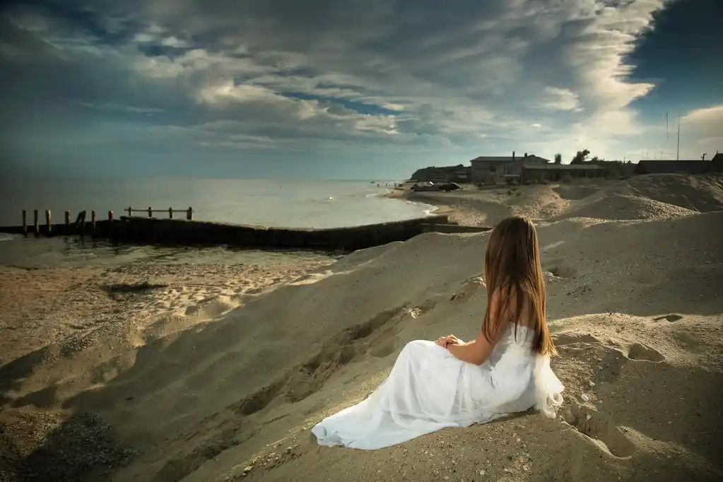 一个女孩坐在岸边看起来在海上.