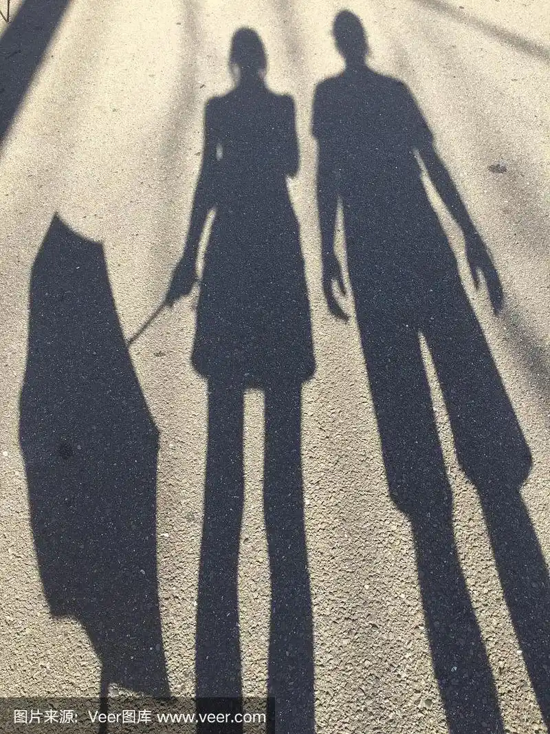 一个女人撑伞和一个男人站在旁边的影子
