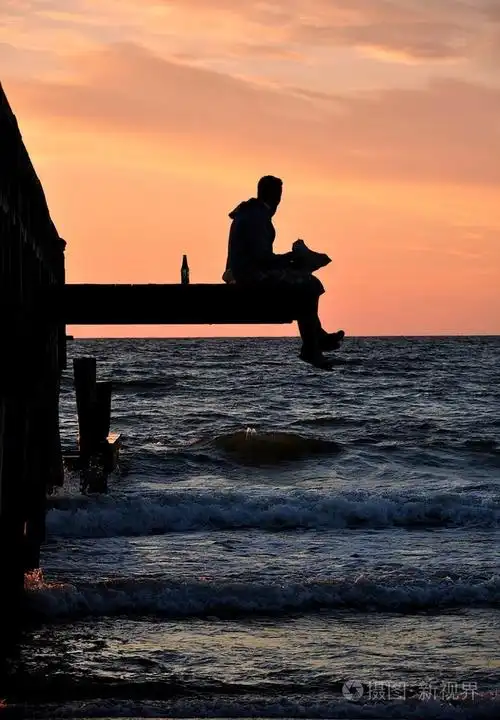 一个男人坐在海边的码头上