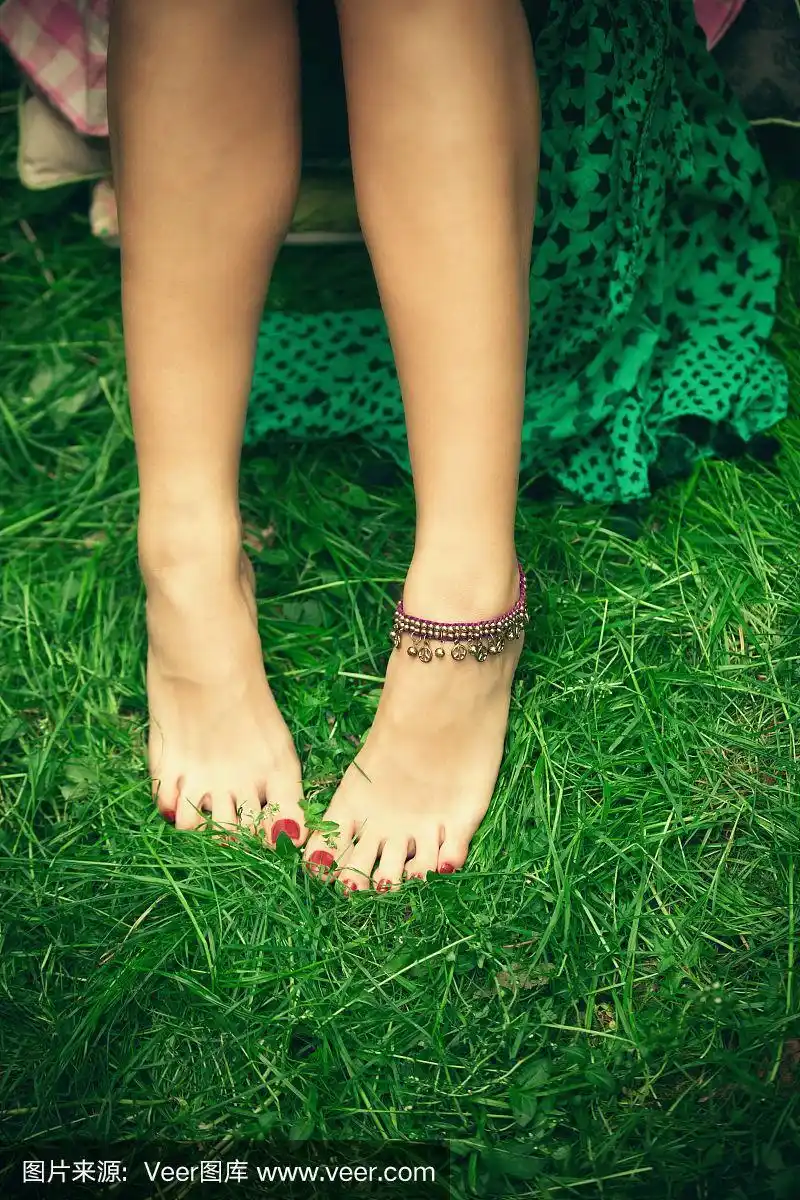 赤脚女人的脚踩在草地上