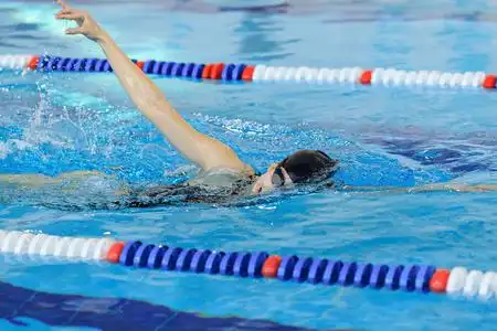 年轻女孩在护目镜和帽蓝色水水池里游泳自由泳描边样式照片