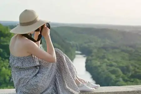 女孩带绿色帽子一个带照相机的女孩的侧面视图.