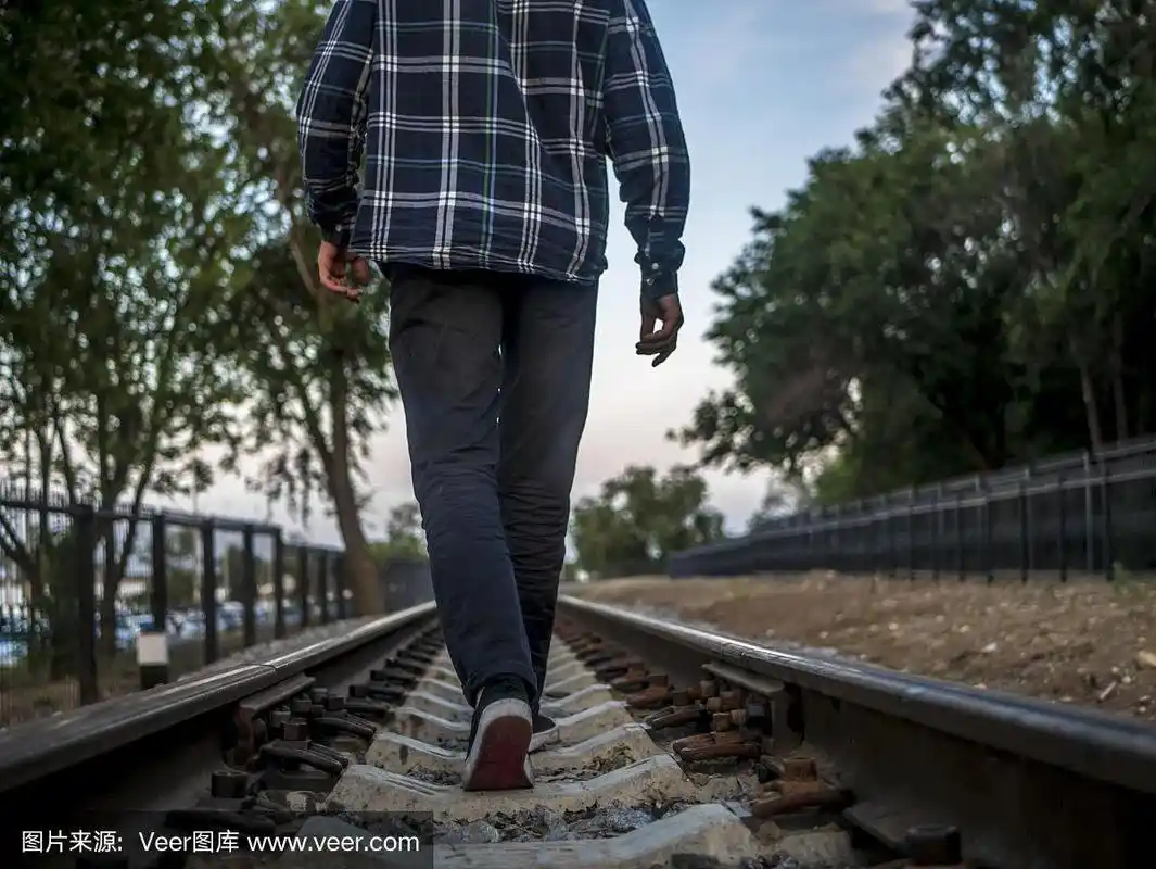 一个孤独的男人远远地走在铁轨上