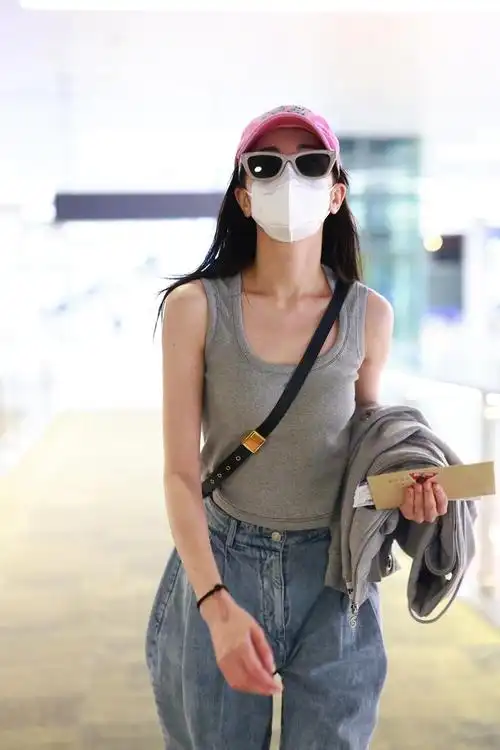 迪丽热巴机场照灰色背心77牛仔裤搭配棒球帽和墨镜