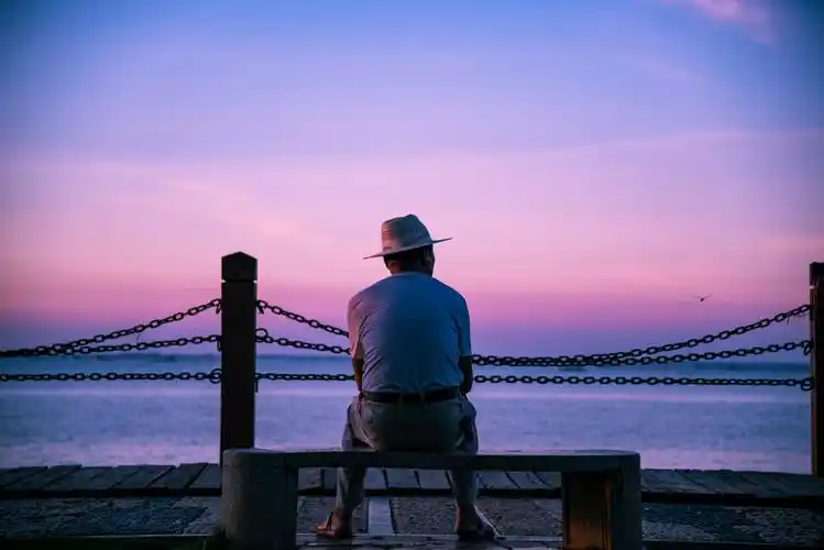 下午,夕阳拉出绛红的晚霞,一位绅士在海边观海