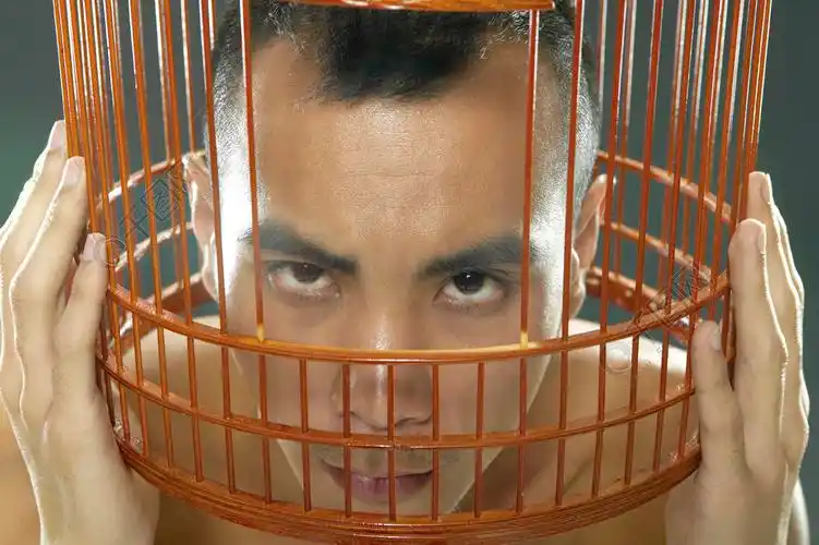 年轻人头在鸟笼里看摄像机