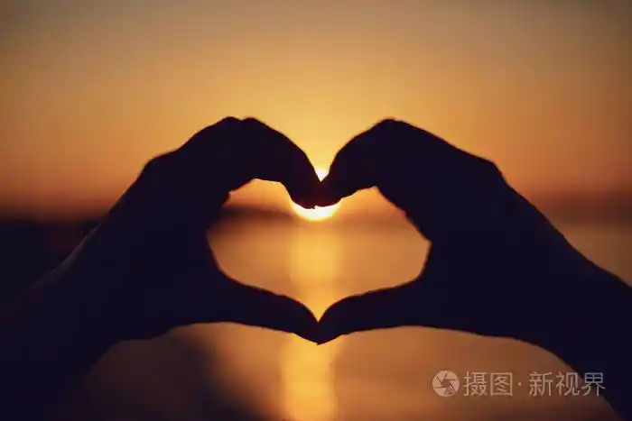 在海边的夕阳下,双手呈心形.照片-正版商用图片2jf1n8-摄图新视界
