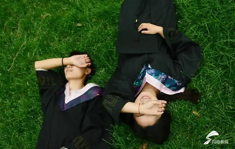 草地,学士服,用手遮住光照,是情侣们毕业照的标配.