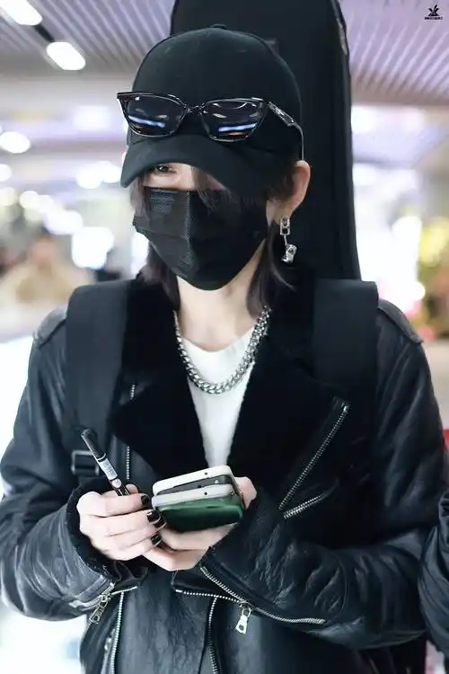 搭配黑色高领内搭,黑色不规则剪裁半裙,黑色长靴,佩戴造型感十足的