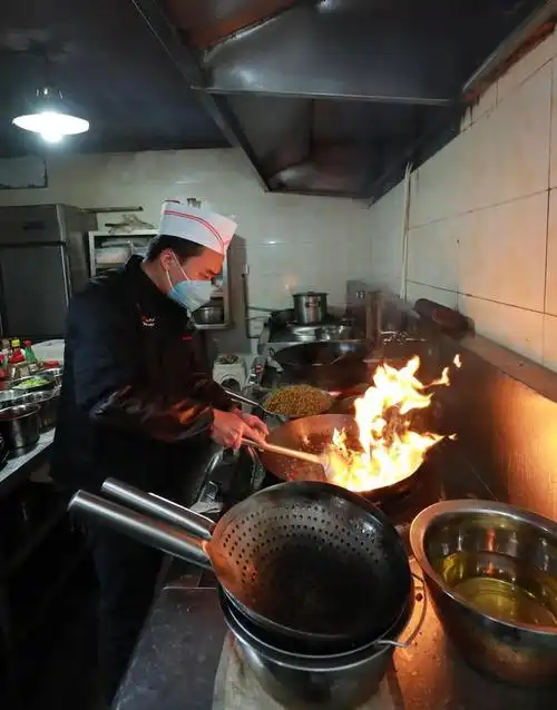 2月18日,厨师曾华在厨房里炒菜.新华社发(韩贤普 摄)