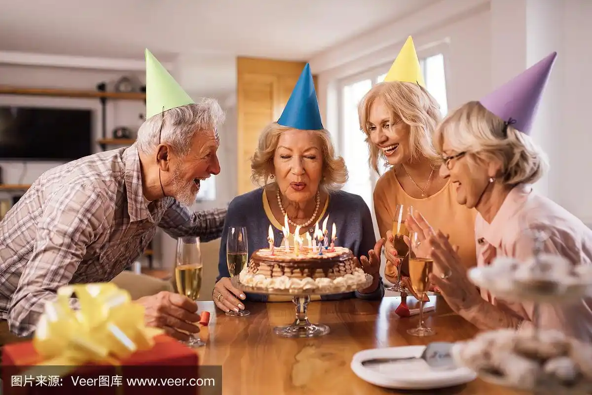 快乐的老女人吹蜡烛在家里的生日派对.