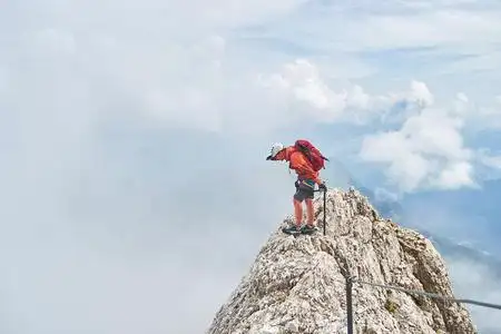一个男人背着一个红色的背包俯瞰着大雾,在意大利的白云石山脉,马尔莫