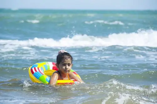 漂亮的小女孩在海里的游泳和玩充气圆