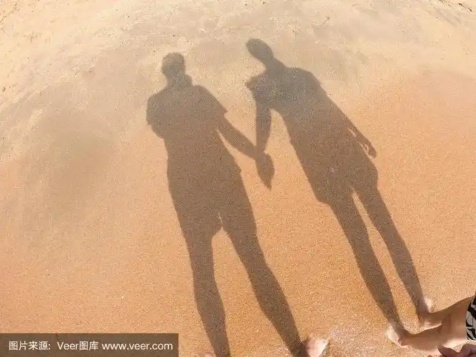 海滩上男人和女人的影子手牵着手.