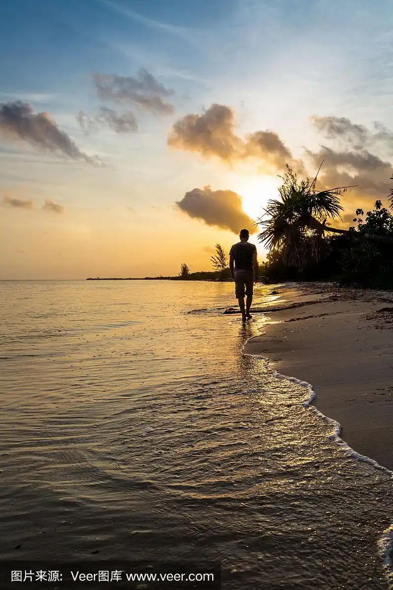 一个人在日出时独自走在海滩上