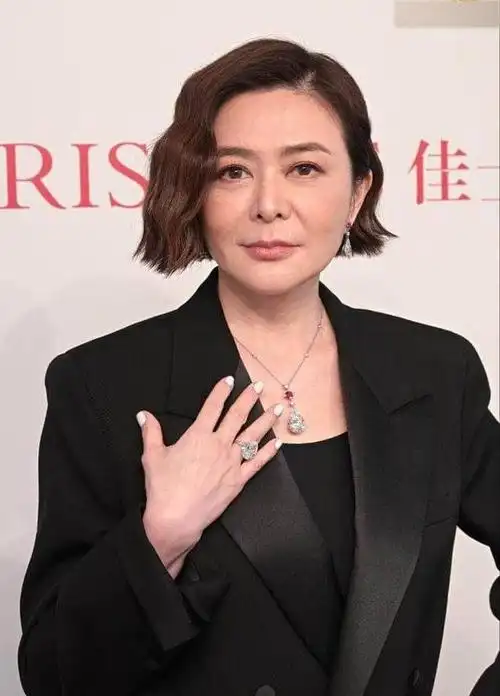 镜头中,关之琳身穿黑色毛绒外套,一头短发,趴在桌子上,精致的容颜和手